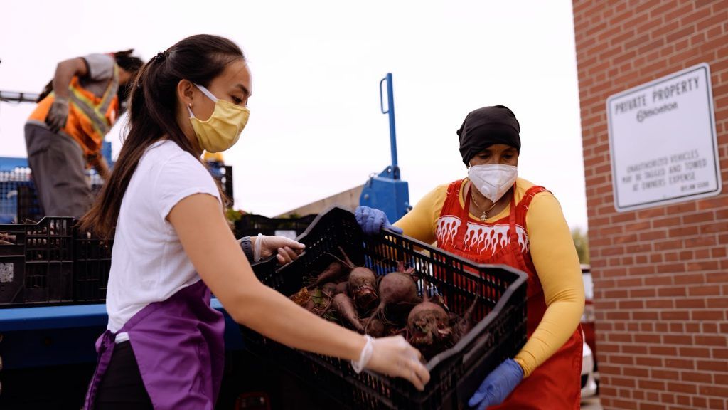 Julia Tran (left) helps Grocery Run worker haul in City Farms vegetable delivery. Credit: City of Edmonton